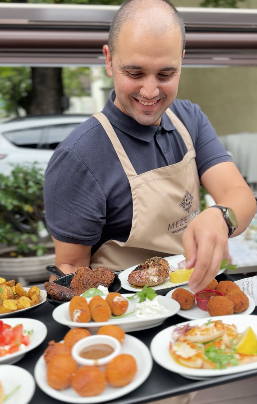 Kellner im Meze Meze serviert griechische Mezedes